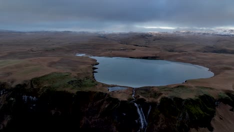 Systrafoss-Wasserfall-Und-See-Systravatn,-Gegen-Bewölkten-Himmel-In-Island---Rückzug-Aus-Der-Luft