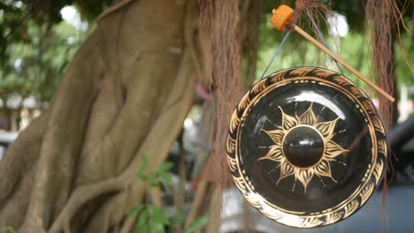 pequeño gong tradicional colgando en el fondo de un viejo árbol banyan a la luz del día. símbolo de la religión budista. fondo natural idílico tropical. meditación zen, retiro y concepto de iluminación.