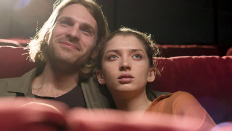 close up view of couple sitting in the cinema watching a movie and talking