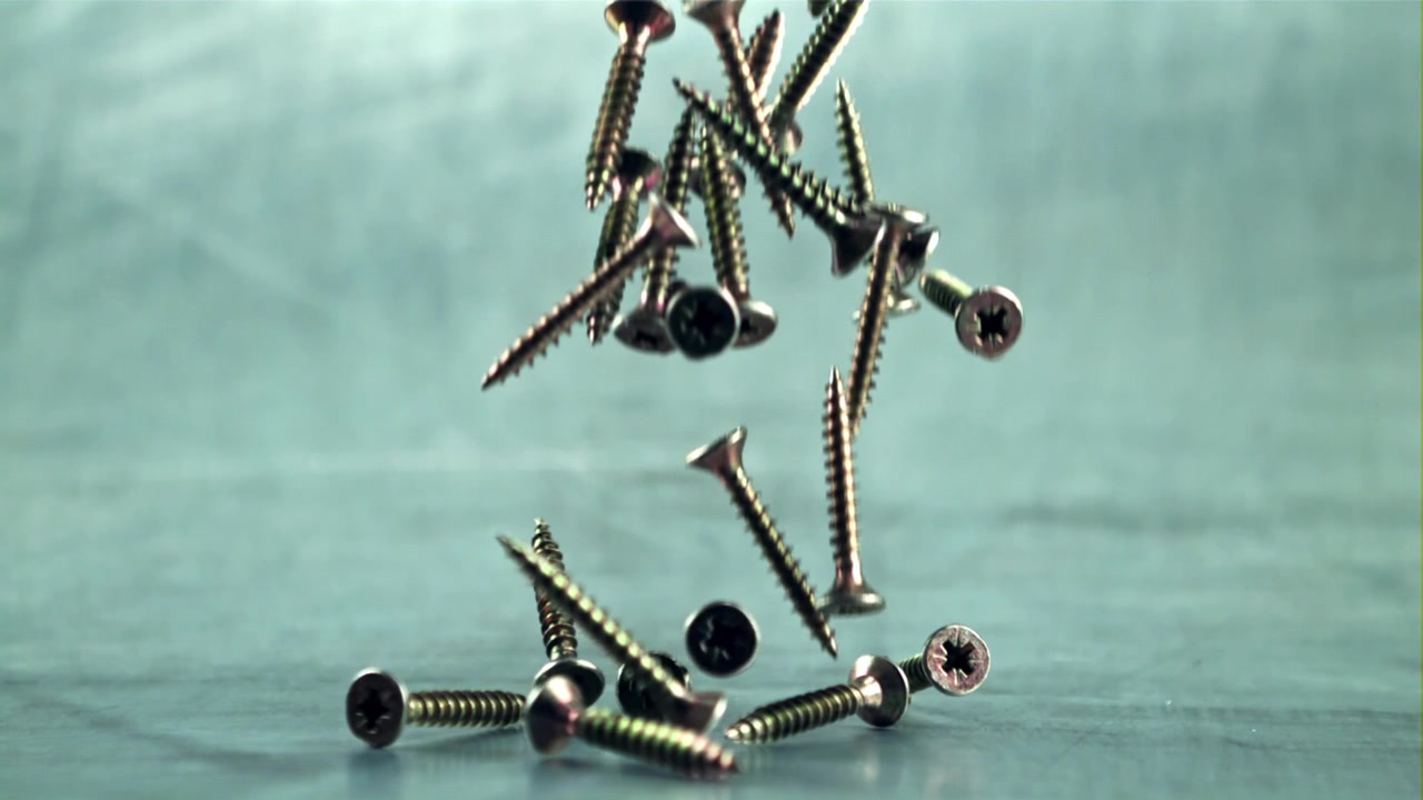 Close-up of Metal Screws Falling onto a Surface in Slow Motion