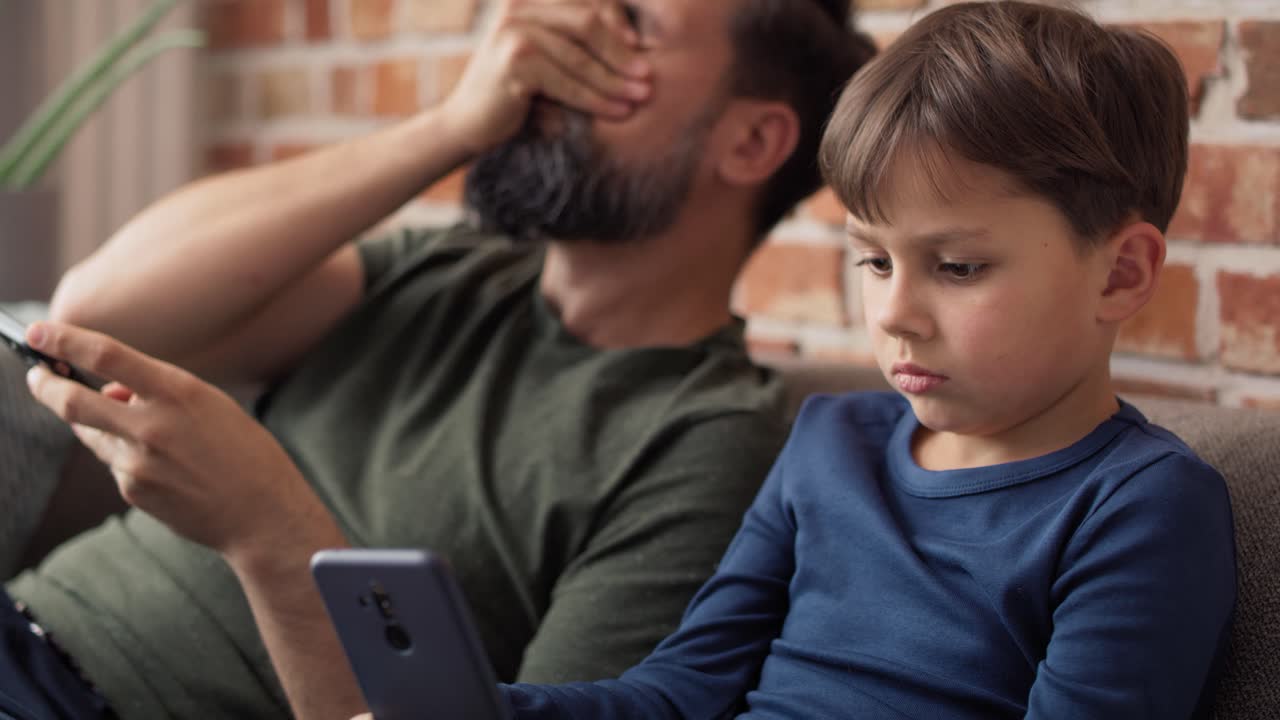 video de padre e hijo sentados y usando teléfonos móviles