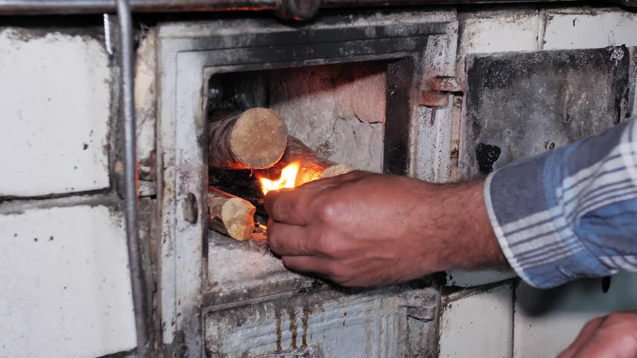 el hombre enciende una madera en una vieja estufa de cocina rústica con un fósforo