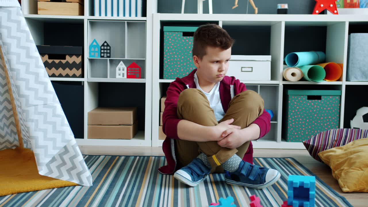 Sad Boy Sitting on Floor in Playroom
