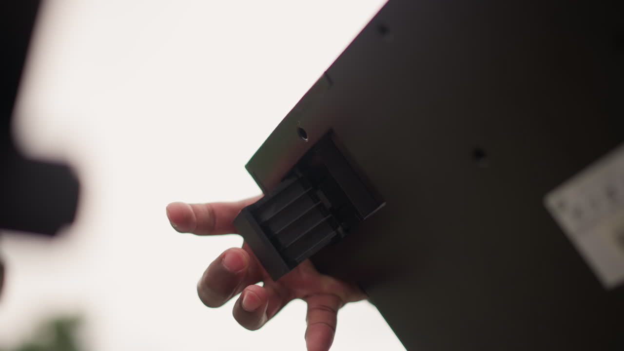 Black hand adjusting equipment mount panel with careful finger placement, shallow depth of field and soft backlight silhouette, precise insertion of rack module into studio hardware, calm professional