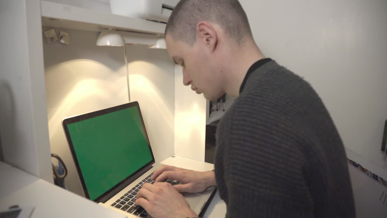 A Man Working On His Laptop With Blank Green Screen At The Office - Closeup Shot