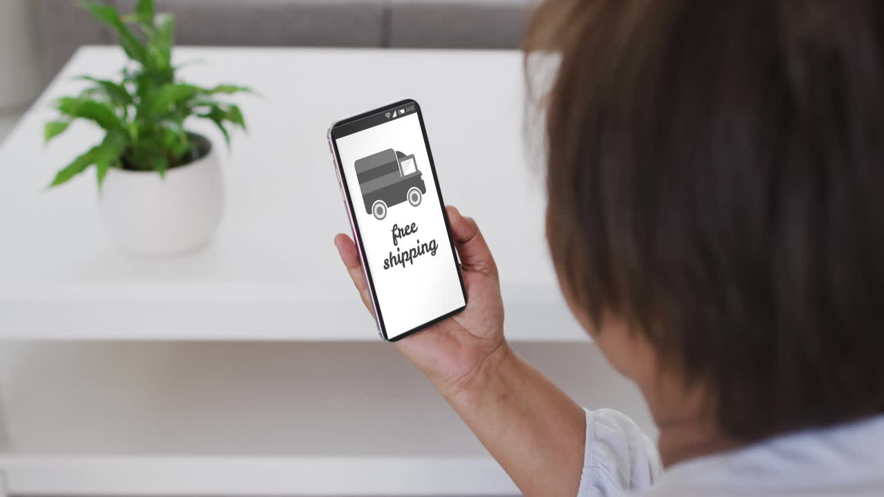 mujer biracial en casa usando teléfono inteligente para comprar en línea, cámara lenta