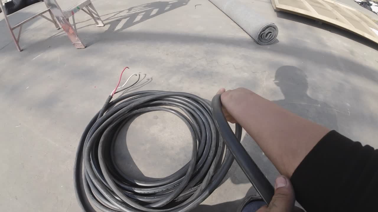 Person, der ruller tykt elkabel op på betongulv