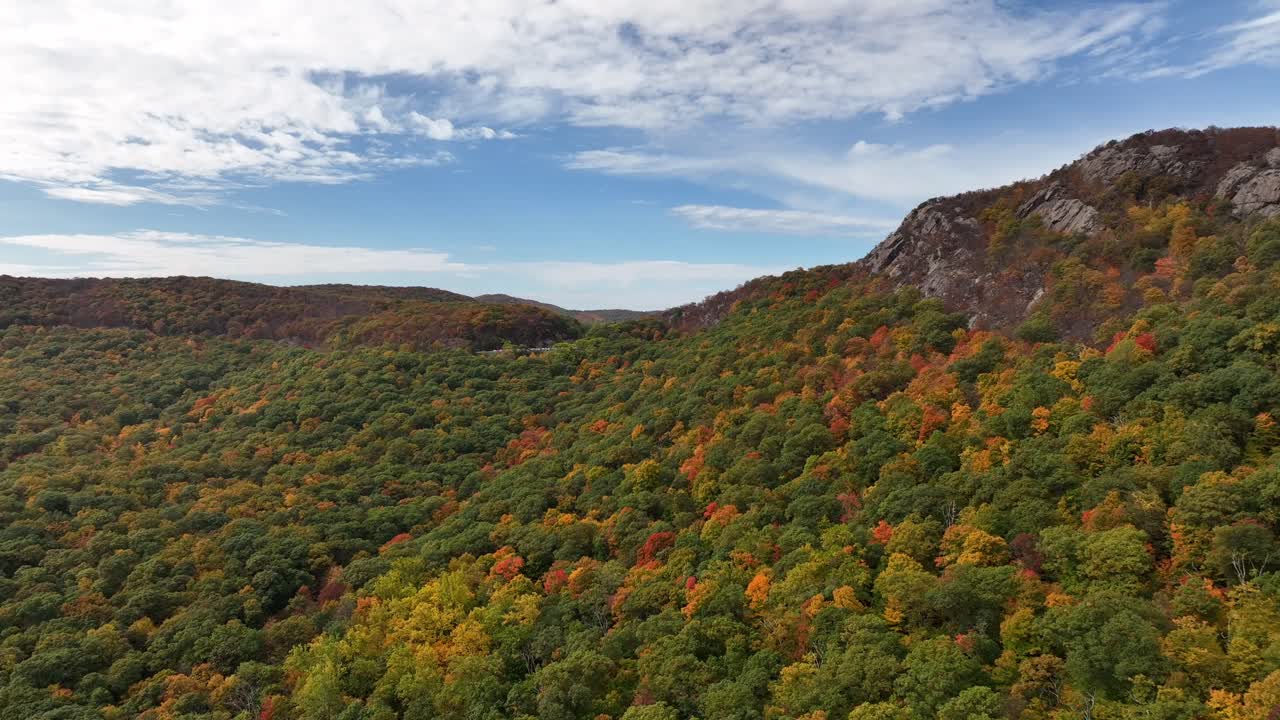 una vista aérea de las montañas en el norte del estado de nueva york durante el cambio de follaje de otoño, en un hermoso día con nubes blancas