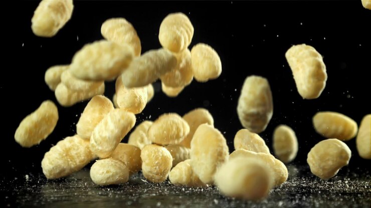 Fresh Gnocchi Falling in Slow Motion onto a Dark Surface