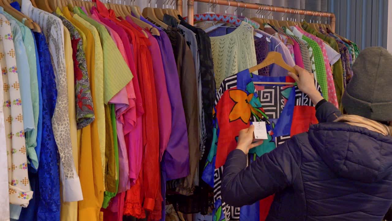 A customer is looking at colorful dresses in an antique store