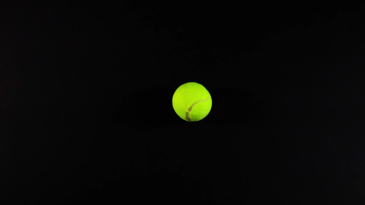 Tennis ball moving against a dark background