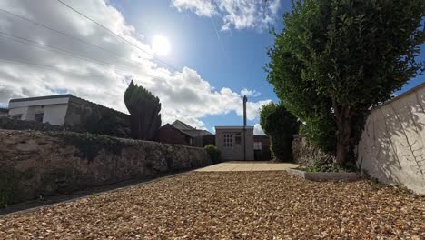 time lapse clouds passing over rural welsh cottage garden casting sunlight shadows on rustic path