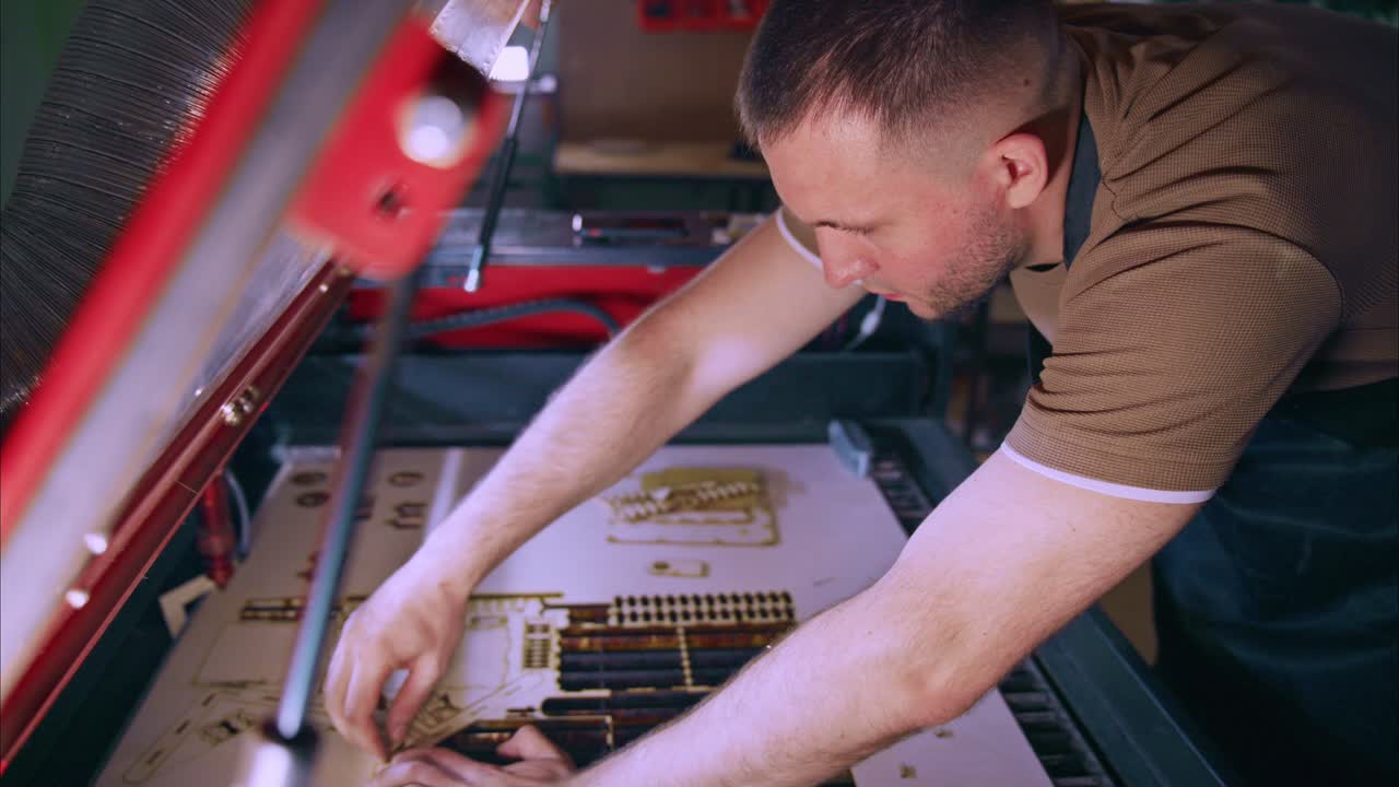 Man Removing Laser Cut Wooden Pieces from Machine