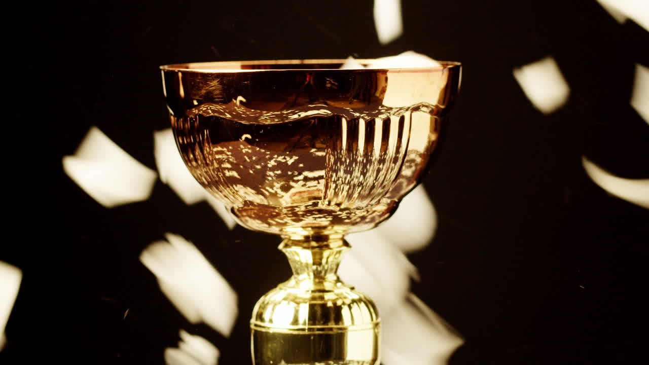 Coppa trofeo dorata con coriandoli che cadono su sfondo nero