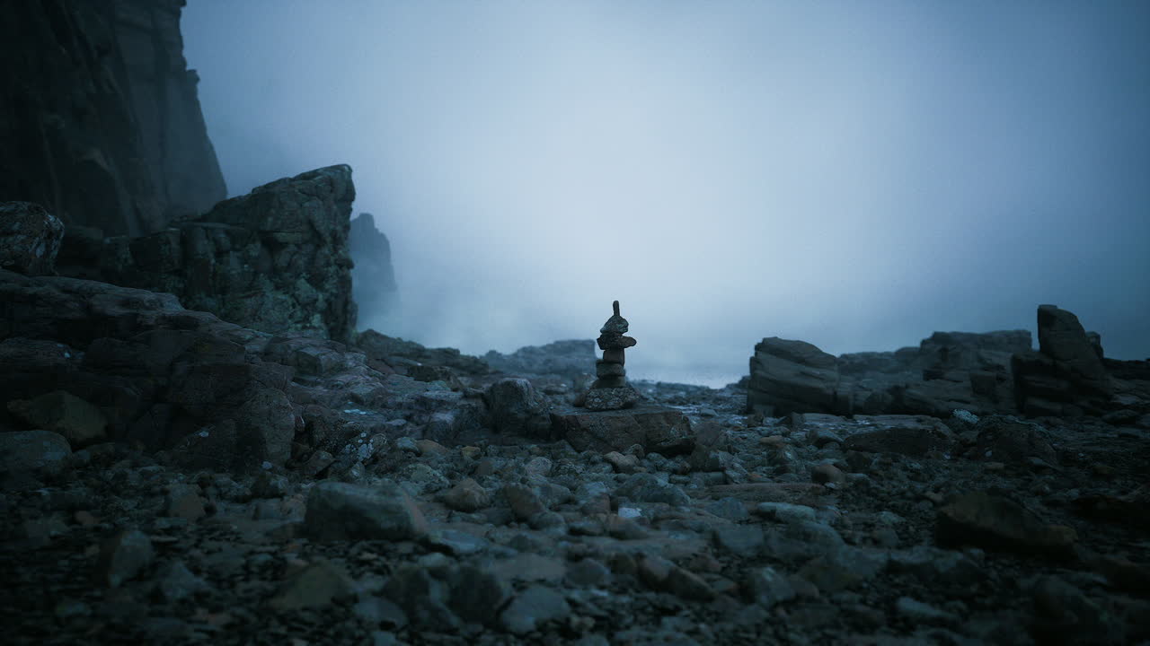 Serene rock formation on a foggy shore during twilight hours
