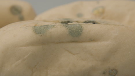 extreme close of fungal mold spots on several pistolet breads against a white background