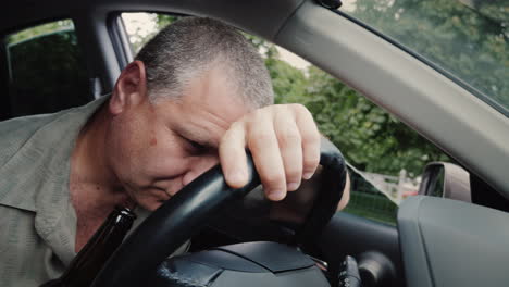 Drunk-Driver-With-A-Bottle-Of-Alcohol-In-His-Hand-Dozing-On-The-Steering-Wheel
