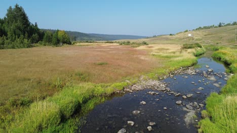 Aerial-Drone-Ascends-Above-Stream-Along-Cariboo-Highway-near-127-Mile-House,-BC,-Canada