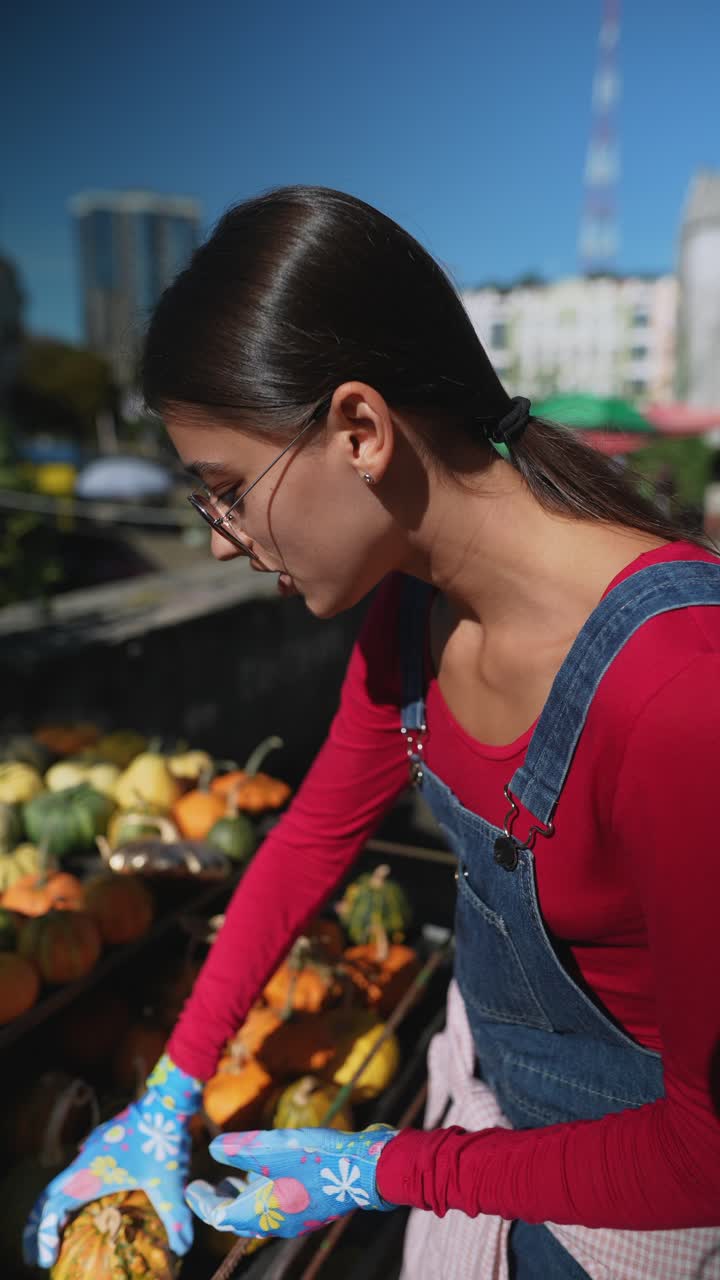 mujer recogiendo calabazas en un mercado de agricultores