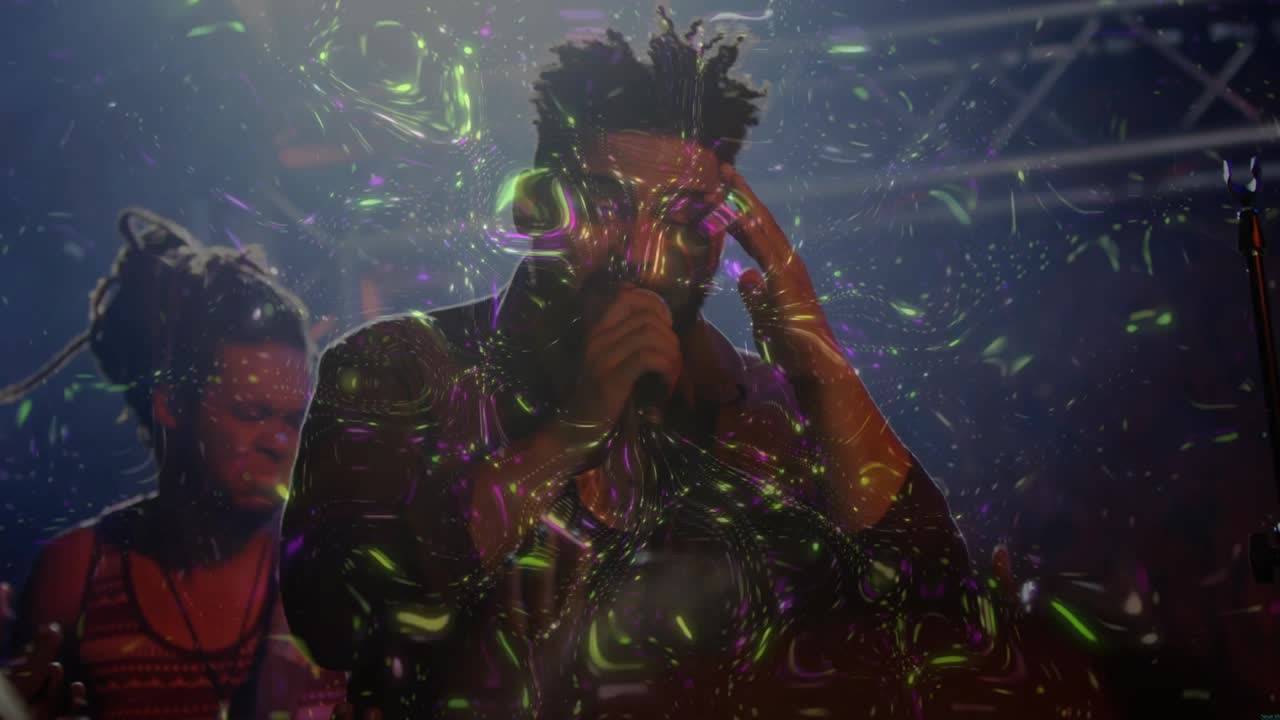 Male singer singing into mic in concert sparking lights painting bubbles on band, engaging fans