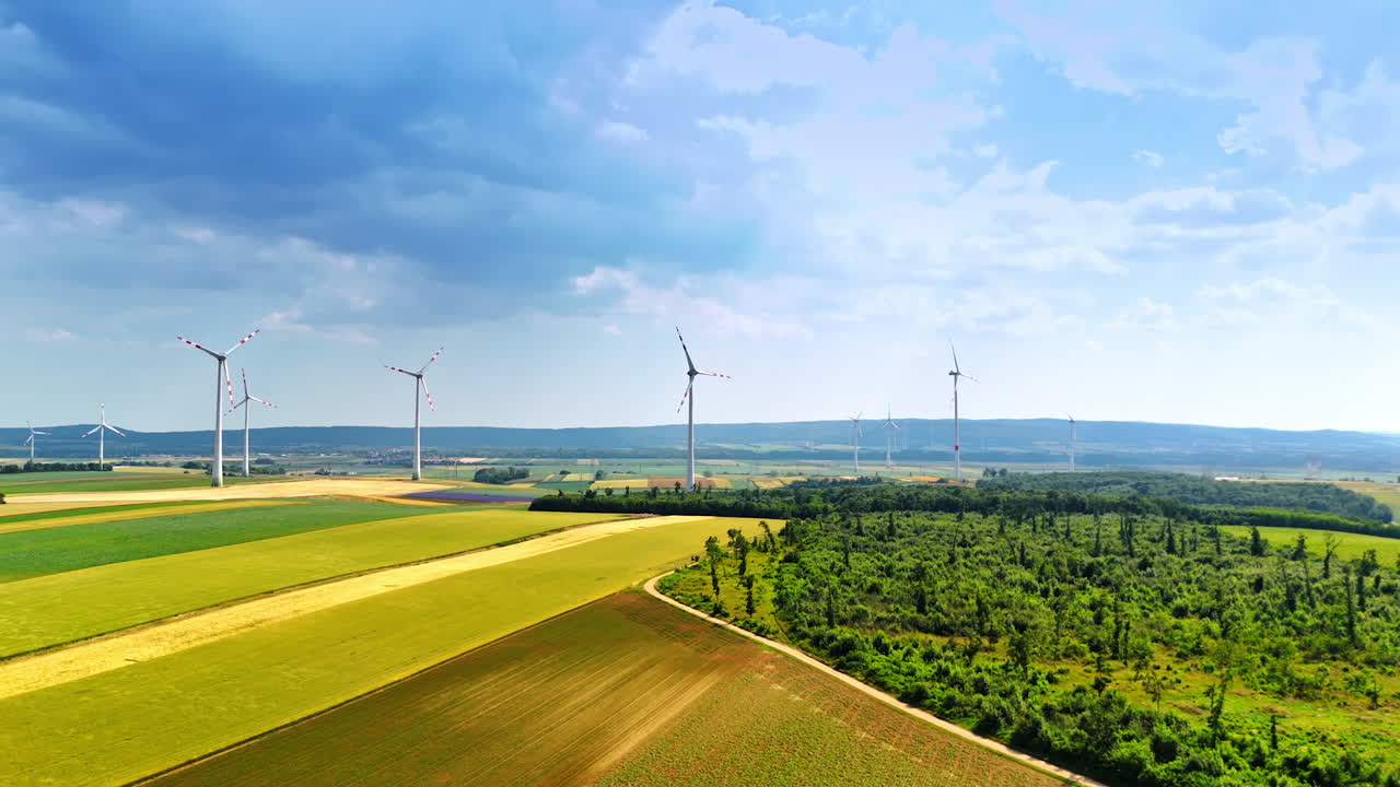 Sustainable energy production in the countryside. Drone footage above the fields under the dramatic clouds in the sky