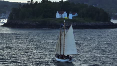 classic wooden sailboat sails past curtis island lighthouse