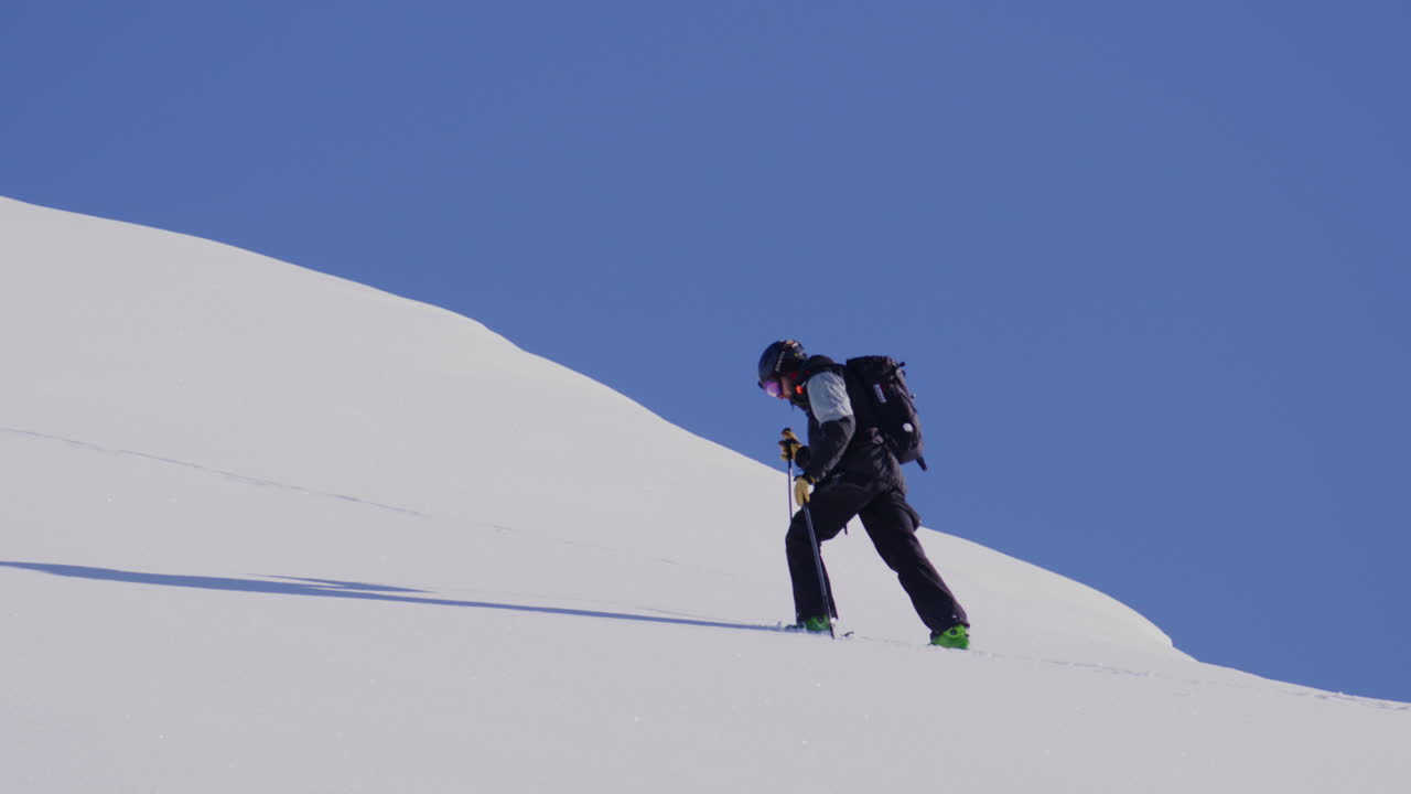 Freeride skier skinning up with Dents du Midi backdrop, then charging steep powder on a bluebird day near Champéry and Avoriaz.