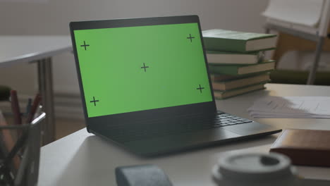 portátil con pantalla verde en el escritorio