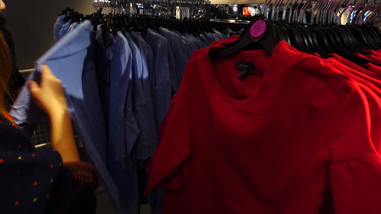 Shopping dans les magasins d'usine en Europe. La jeune fille choisit des vêtements. Soldes et réductions