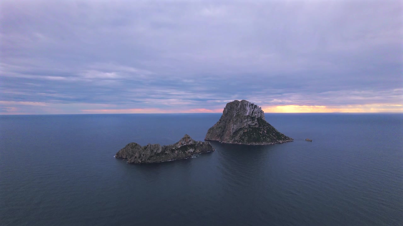 Ripresa aerea in 4K con drone di Es Vedrà al tramonto, Ibiza, Spagna. L'iconica isola rocciosa emerge dal Mar Mediterraneo mentre una calda luce dorata illumina la costa e le acque circostanti