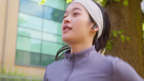 Close-Up-Of-Young-Woman-Exercising-Running-Along-City-Street-Wearing-Wireless-Earbuds-2