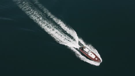 aerial tracking shot of small speed boat speeding away in blue ocean water, tenerife spain