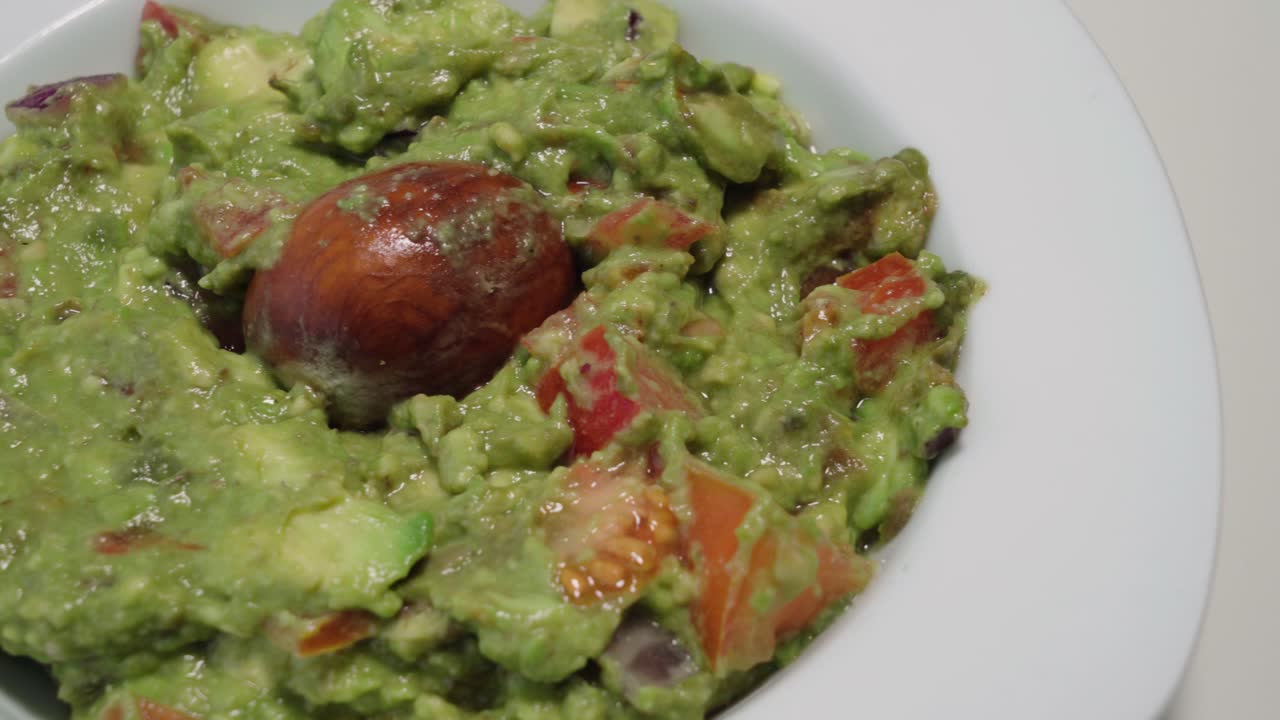 guacamole con hueso de aguacate, bandeja de cierre a la derecha sobre fondo blanco aislado