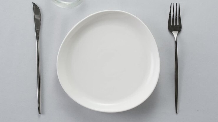 Mise en place elegante con piatti bianchi, posate e bicchieri per una cena raffinata in un ristorante di lusso.