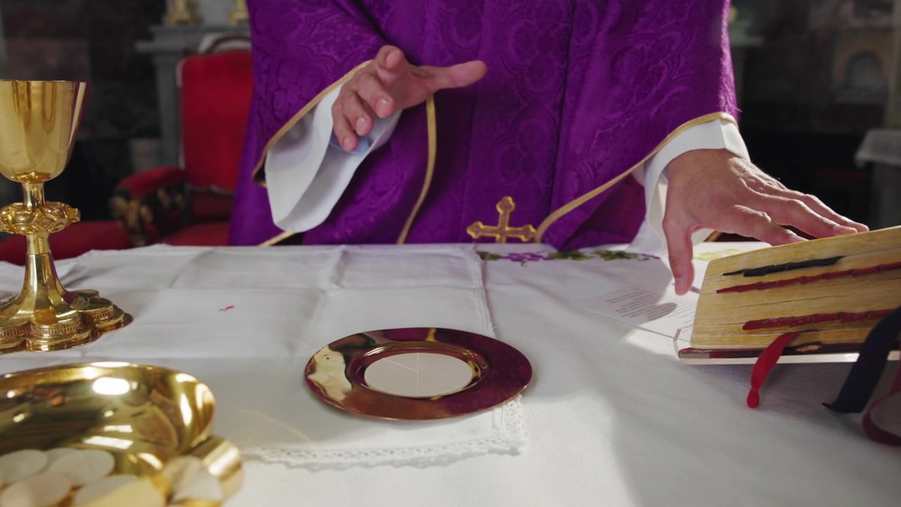 Katolický kněz sloužící eucharistickou liturgii a čtoucí z liturgické knihy položené na oltáři.