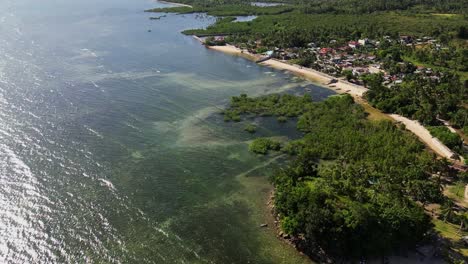 Aerial forward shot of scenic shallow ocean reef along tropical island village at Yocti, Catanduanes, Philippines.