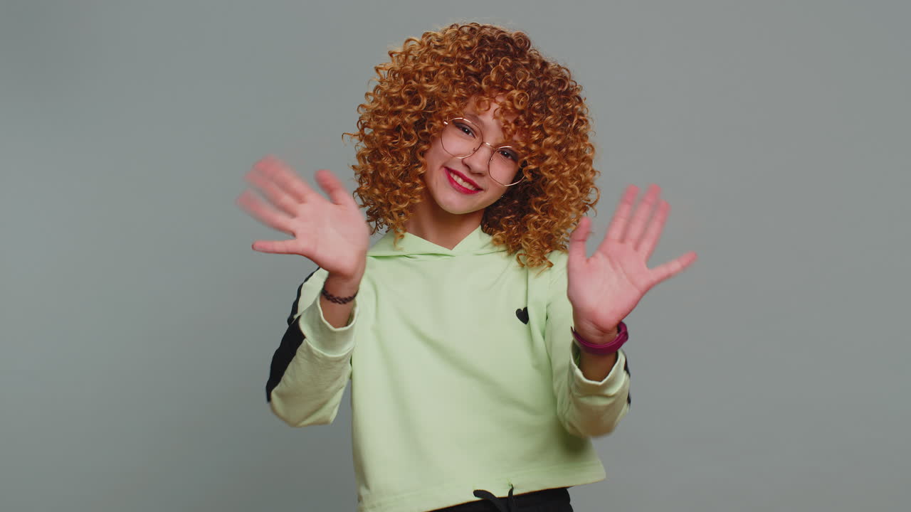 Young teen school girl kid smiling friendly gesturing hello or goodbye welcoming waving hands