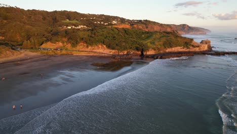 people at sandy beach of muriwai at sunrise on maukatia bay shore in new zealand