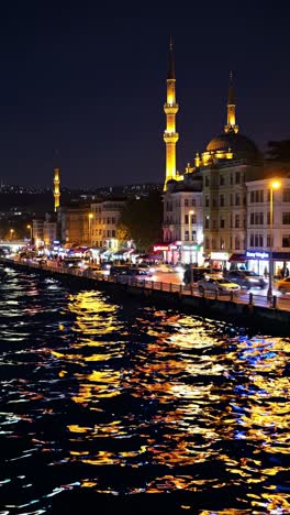colorful lights reflecting off the water’s surface, illuminating buildings, bustling traffic, and a majestic mosque at night, creating a vibrant and tranquil urban scene