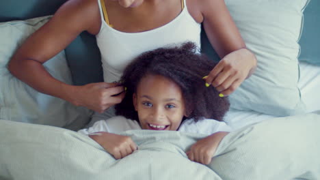 little girl hiding under blanket while her mum stroking her hair