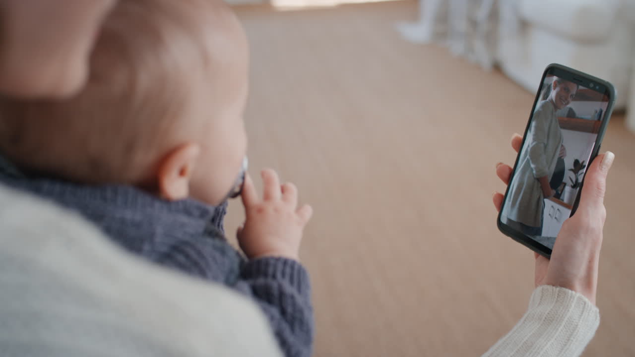 若い母親と赤ちゃんがスマートフォンを使ってビデオチャットし ⁇ 妊娠中の友人とチャットし ⁇ 携帯電話の画面で母性のライフスタイルを共有している腹を示しています ⁇