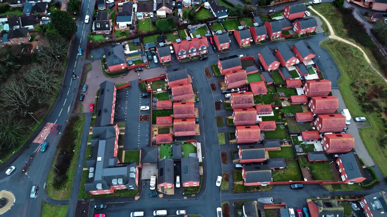 Flygbilder tagna med drönare över ett lokalt engelskt villaområde i södra England under blå timmen i solnedgången. Med livligt trafikerade vägar och en lugn atmosfär med trädgårdar, träd och en damm