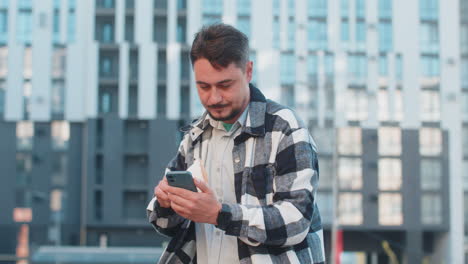 happy rich mature business man using smartphone and counting money euro on downtown city street