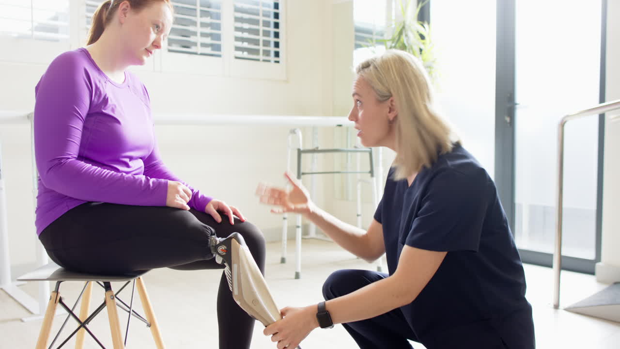 Adjusting prosthetic leg, therapist helping woman in rehabilitation session
