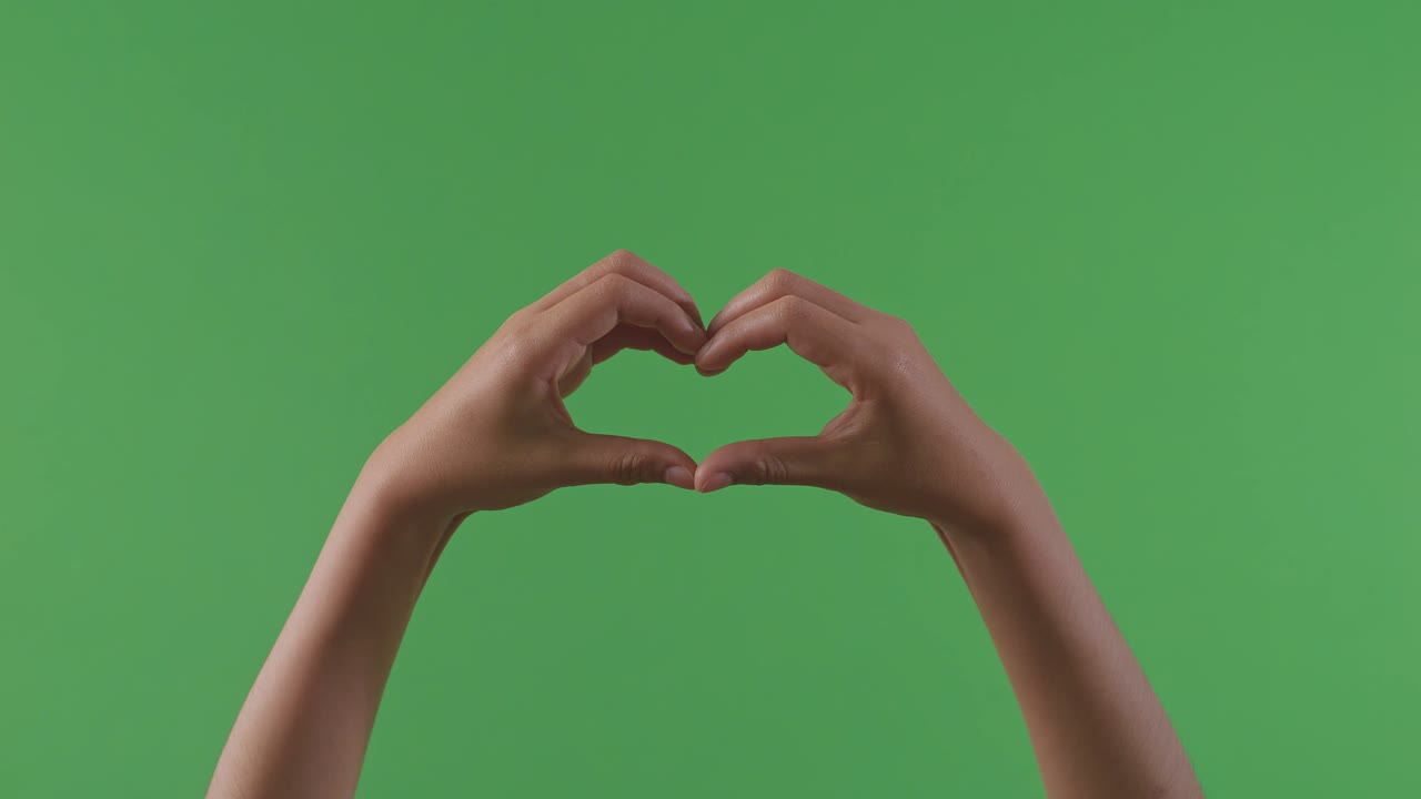 manos formando una forma de corazón en una pantalla verde