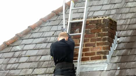 hombre en la escalera instalando antena de televisión digital en el techo de la casa