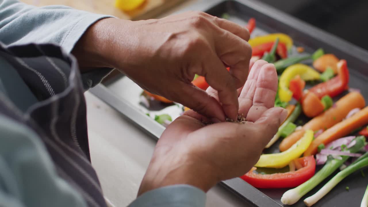 sección media de una mujer mayor asiática rociando orégano sobre una ensalada de verduras