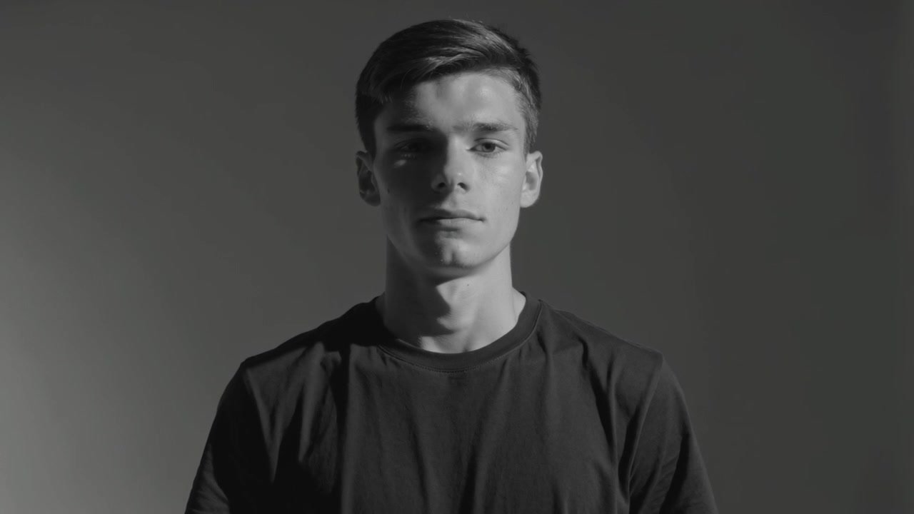 Camera rolling, man wearing dark tee making small head movements in studio with side lighting