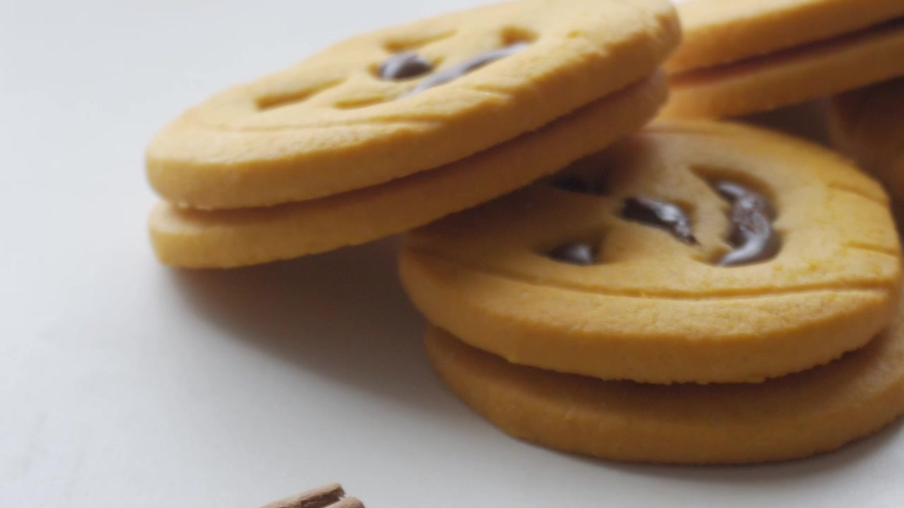 Primo piano di gustosi biscotti di Halloween a forma di zucche con facce di cioccolato, carrellata lenta, spazio per il testo, cannella come decorazione.