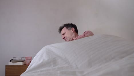 adult man waking up in the morning, checking time on his phone and take pills on bed